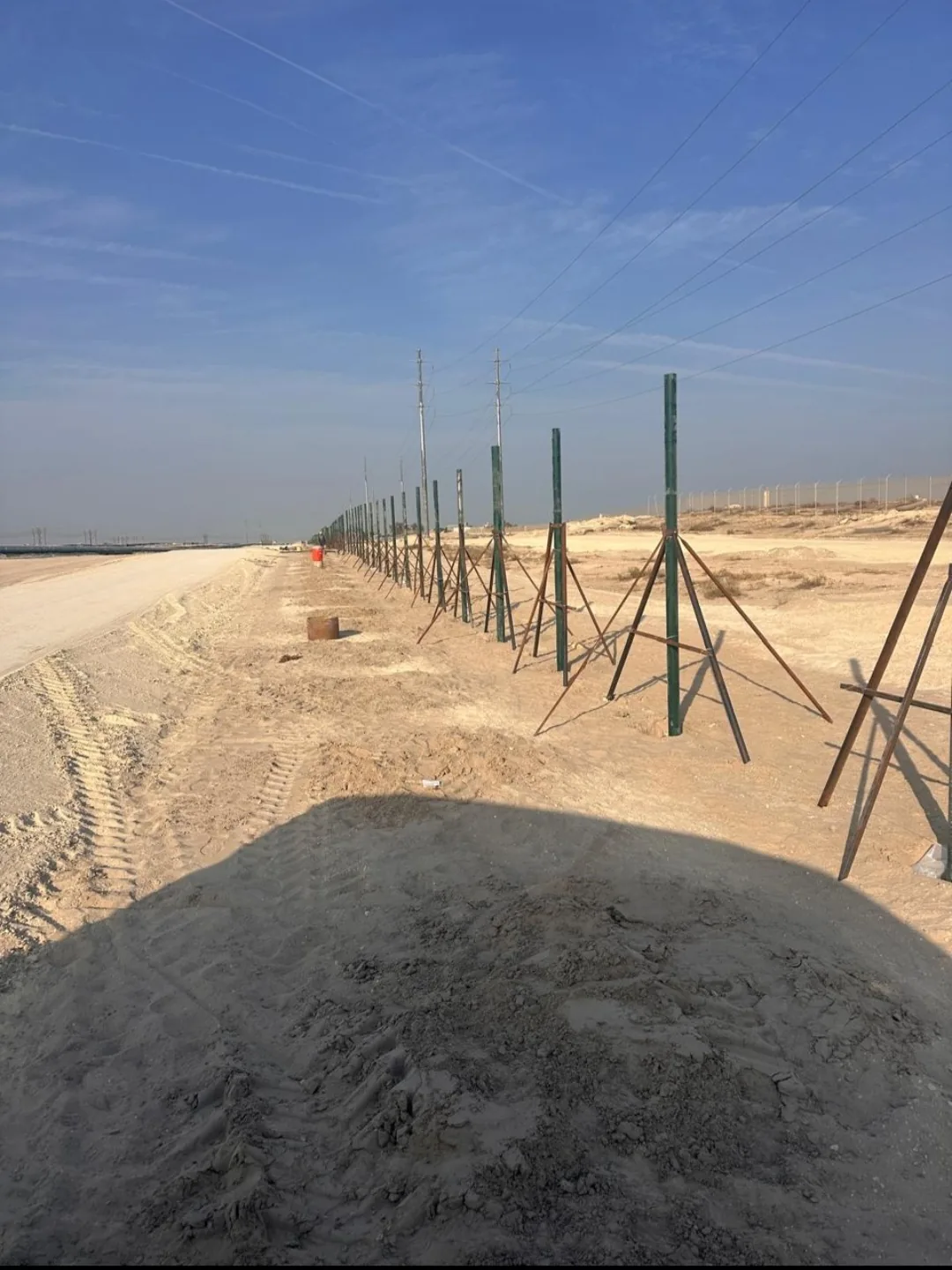 Long row of fence posts under construction around a project