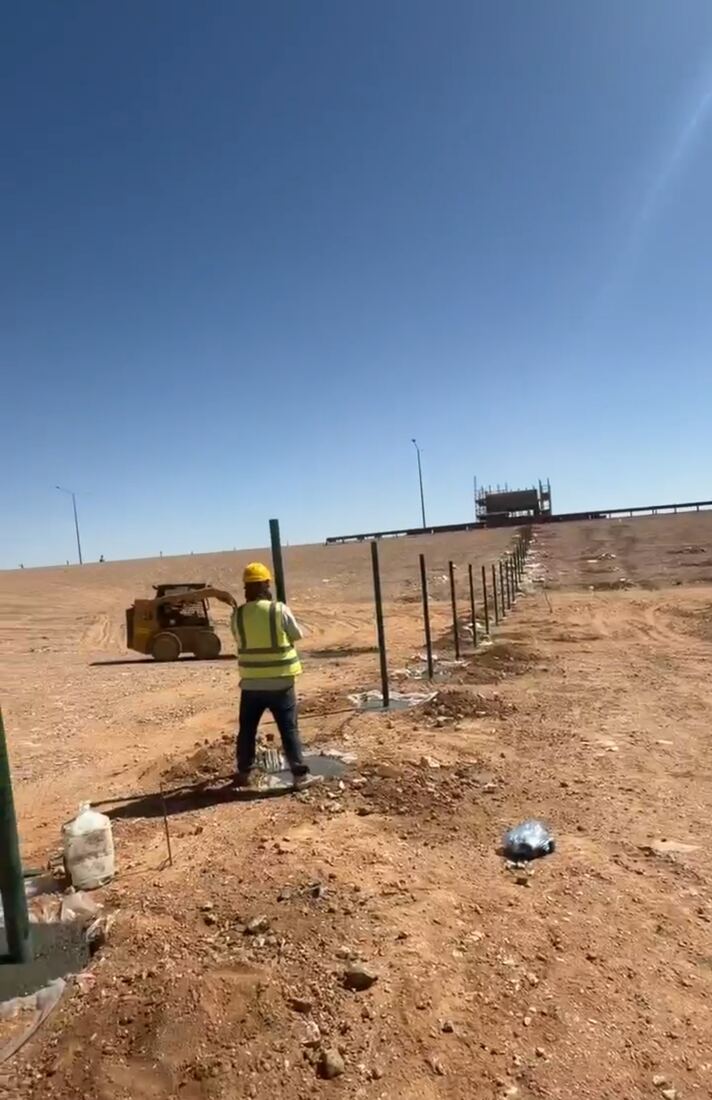 فني يركب سياجًا شبكيًا حول موقع زراعي
